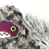 Close up of a furry creature with gray, curly texture. It has a dark purple face, big green eyes, and toothy grin . Textures white background.