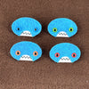 Four oval shaped teal faces with different eye colors and pointed teeth sit atop a brown fleece background.