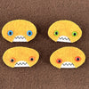 Four oval shaped orange faces with different eye colors and pointed teeth sit atop a brown fleece background.