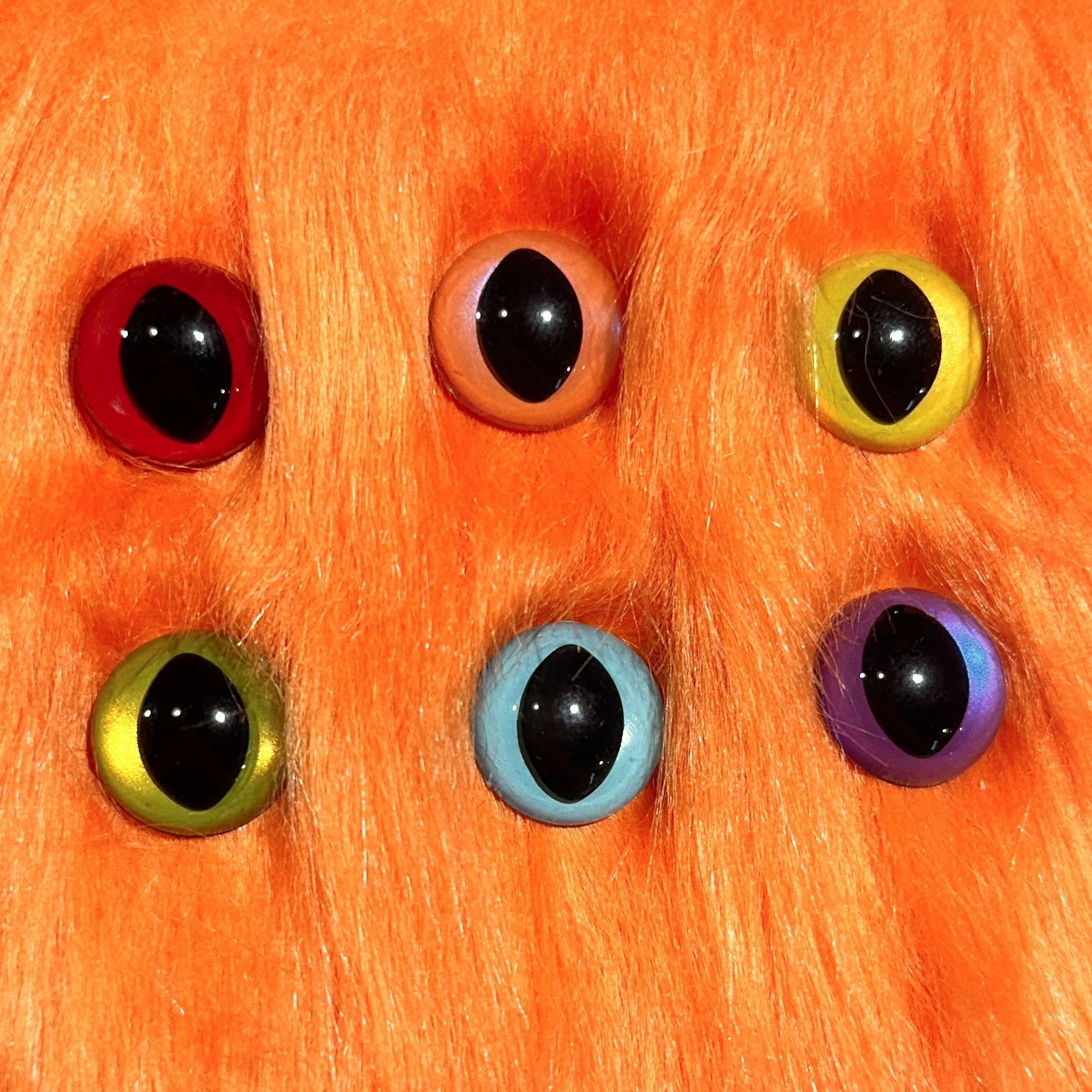 Slit pupil safety eyes in six colors lay atop orange faux fur.