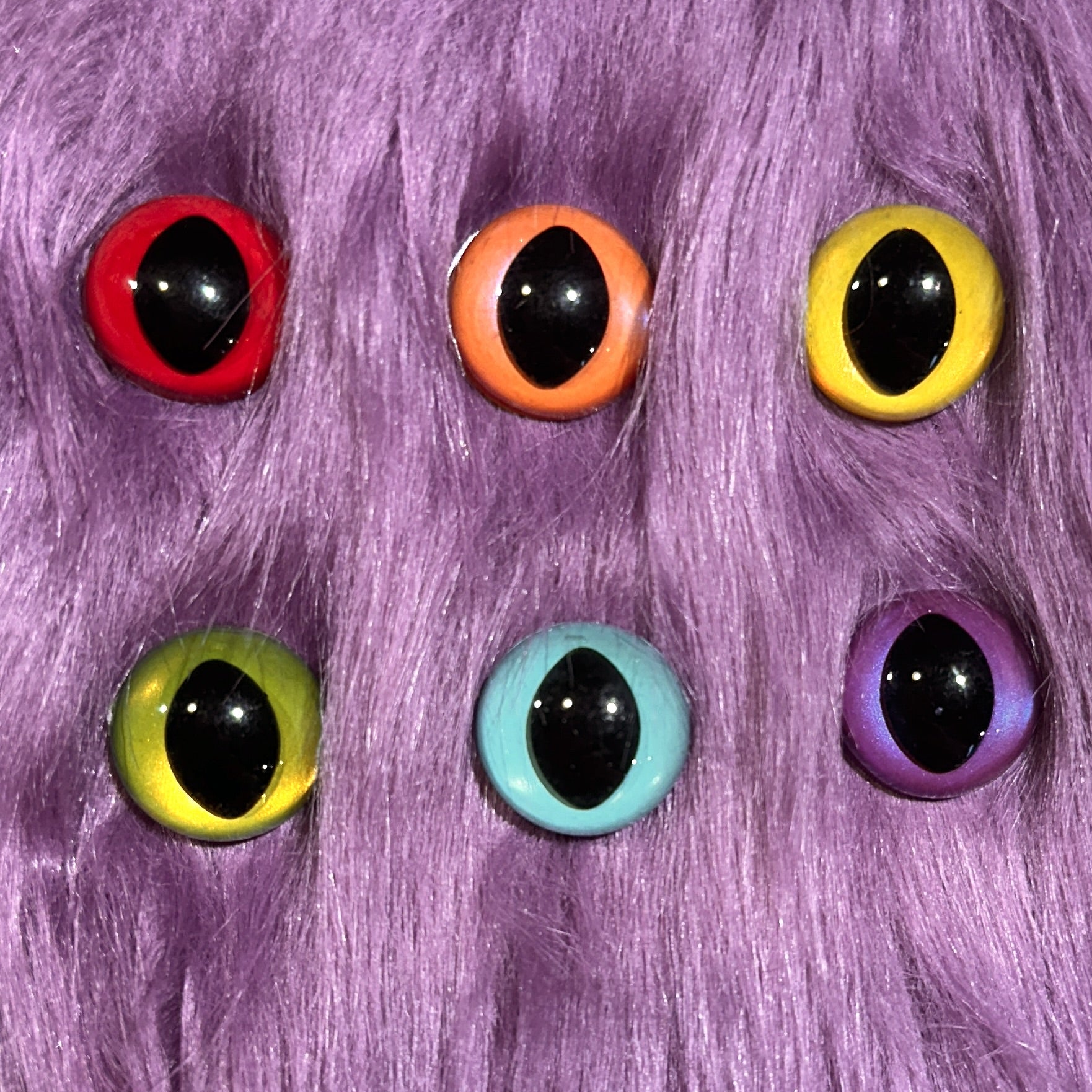 Slit pupil safety eyes in six colors lay atop purple faux fur.