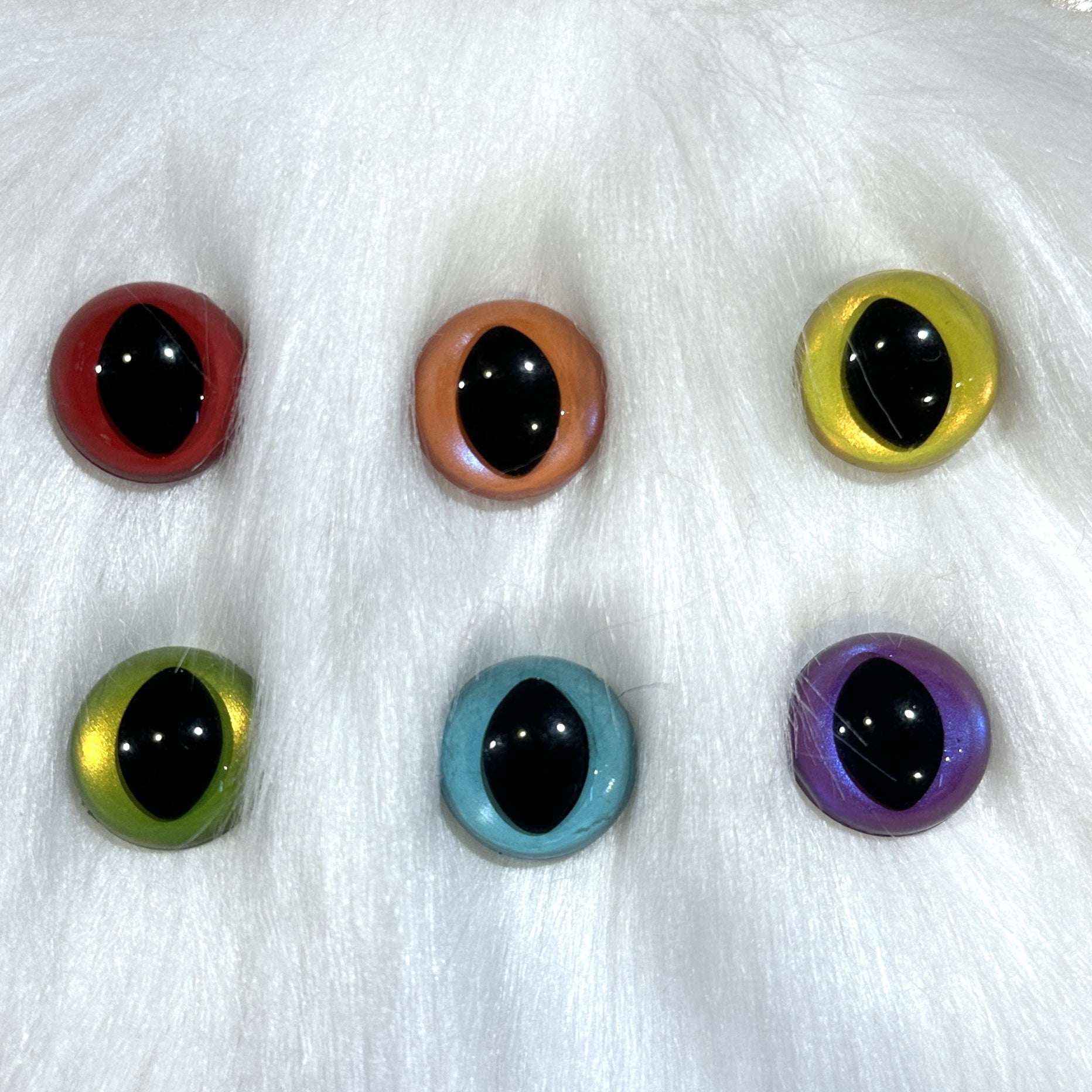 Slit pupil safety eyes in six colors lay atop white faux fur.