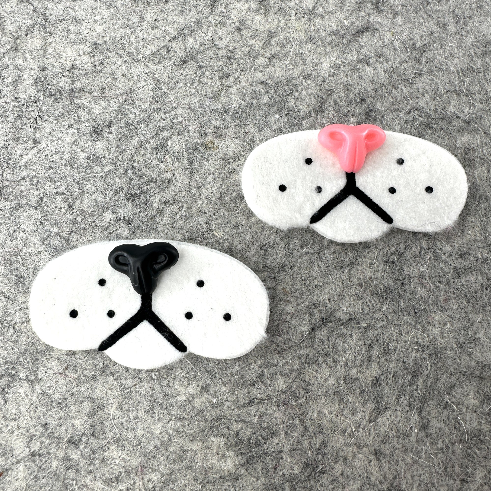 Two plush cat muzzles, one with a pink nose and one with a black nose.