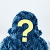 A dark blue fuzzy Woolly Yeti faces away from the camera. A large yellow question mark is attached to their back. The smooth, light gray background evokes a whimsical and mysterious atmosphere reminiscent of Seattle WAs enigmatic charm.