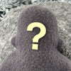 A small grey fleece figure with a question mark where his face should be stands in front of a textured grey background.