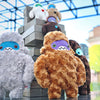 A group of six sasquatch plush, three large and three small, sit atop a large jenga block pile looking adorable.