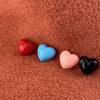 A row of four different colored plastic hearts sit atop of a orange fleece background.