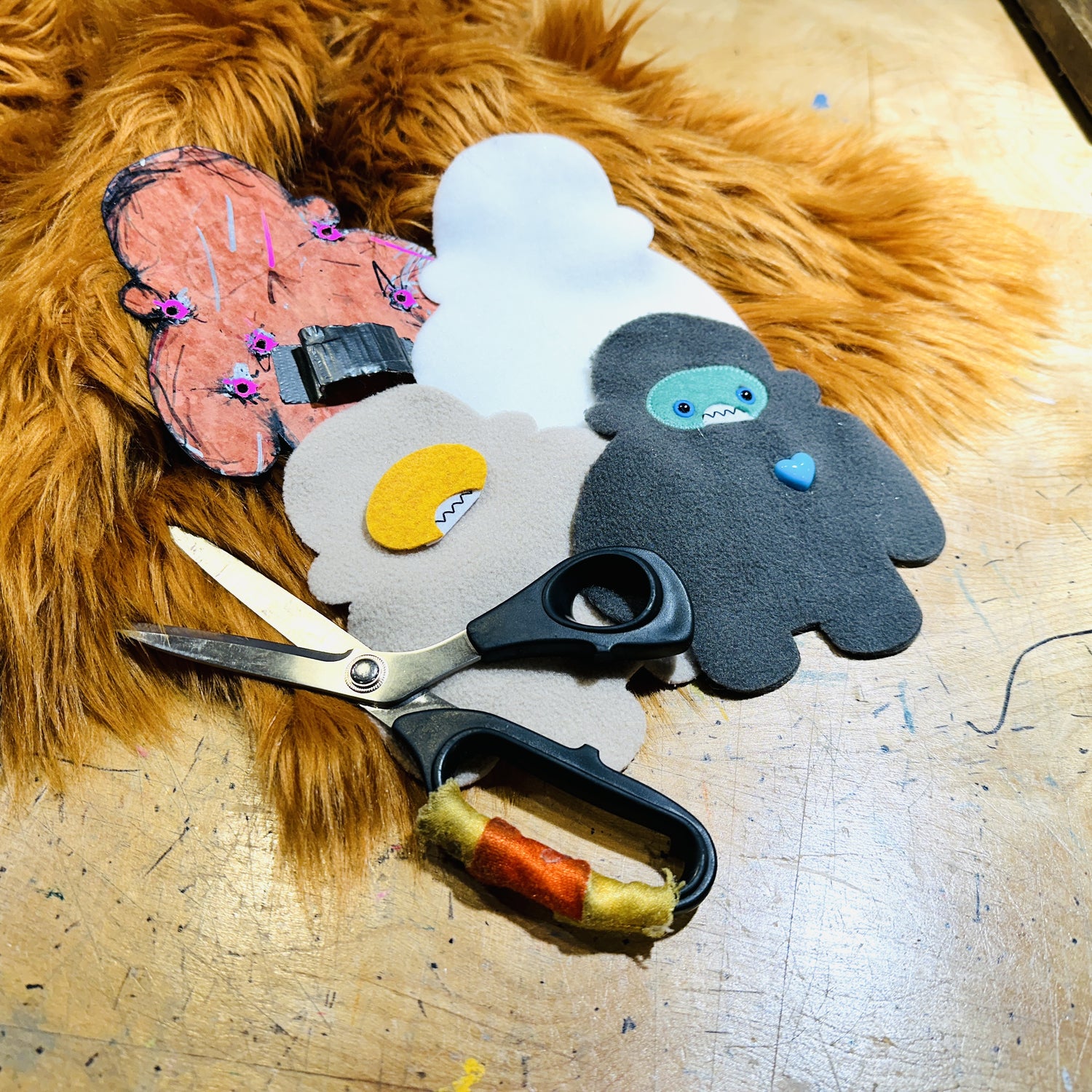 A pile of half finished plush animals lay strategically upon each other with scissors and copper faux fur.