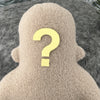 A sand colored fleece figure with a question mark for a face sits against a grey textured background.