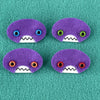 Four oval shaped purple faces with different eye colors and pointed teeth sit atop a teal fleece background.