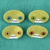 Four oval shaped green faces with different eye colors and pointed teeth sit atop a teal fleece background.