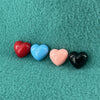 A row of four colorful plastic hearts sit atop a teal fleece backdrop.