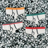 Four pair of various band colors of tiny underwear sit on top of a textured white background.