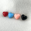 A row of four plastic colored heart in different colors sit atop a white fleece backdrop.